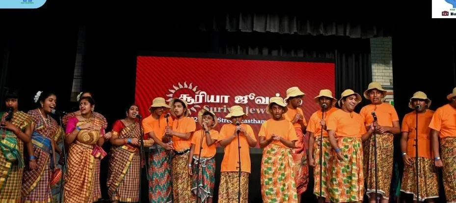 Children in orange performing together on stage.